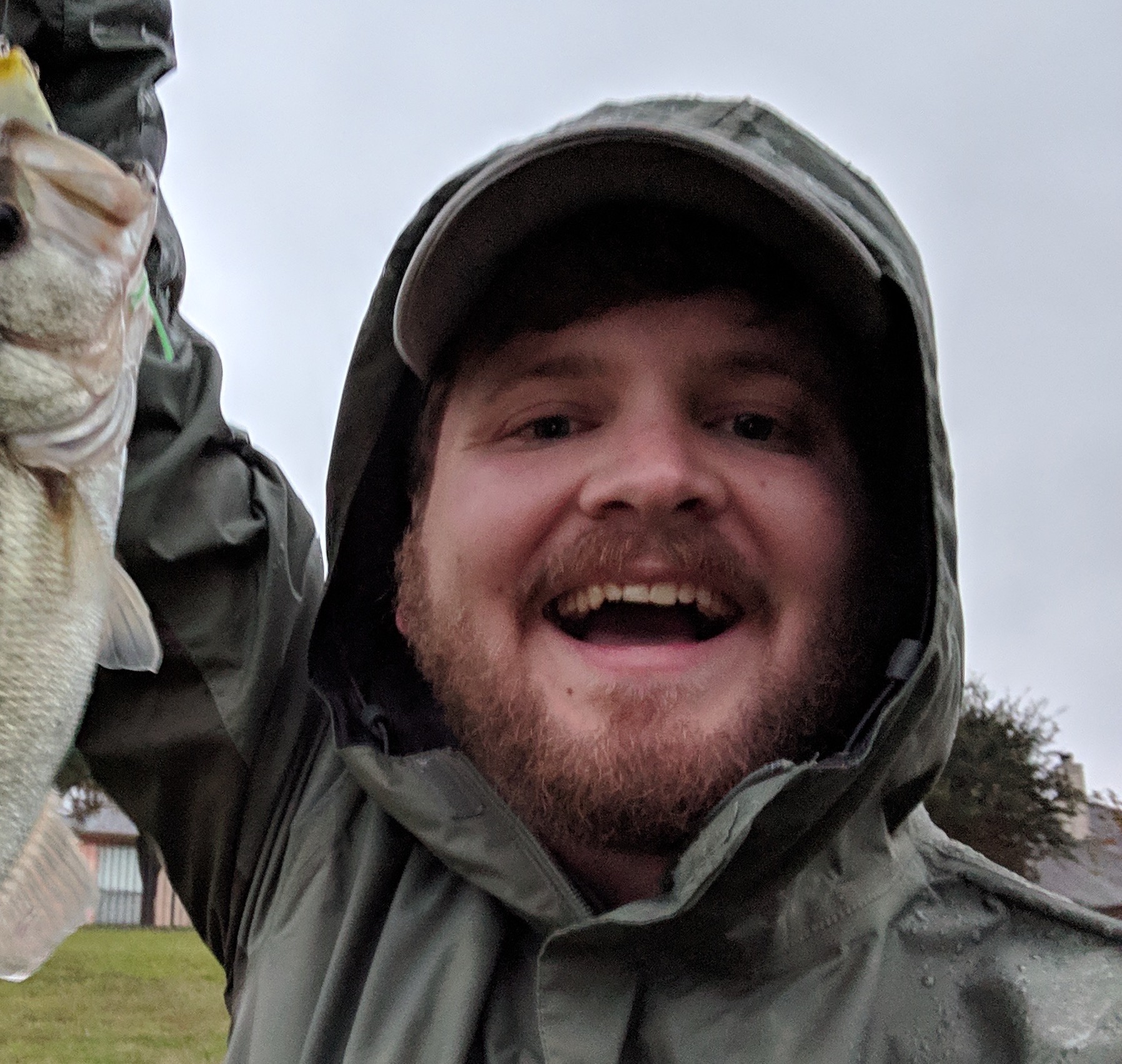Male holding Bass fish in a raincoat